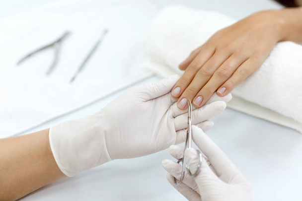 Manicure. Hands Removing Cuticle From Woman Hand With Scissors - Fotó, kép