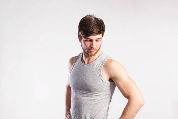 Handsome fitness man in gray tank top shirt, studio shot. - Фото, изображение