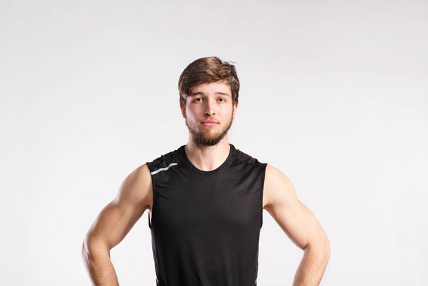 Handsome fitness man in black sleeveless shirt, studio shot. - Fotó, kép