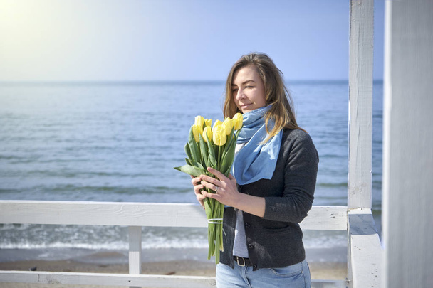 Donna felice con fiori vicino alla riva del mare
 - Foto, immagini