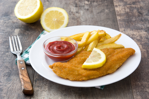 Wiener schnitzel with fried potatoes on wooden background - Photo, Image