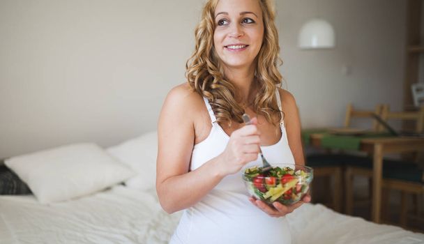 Pregnant woman eating salad - Фото, изображение
