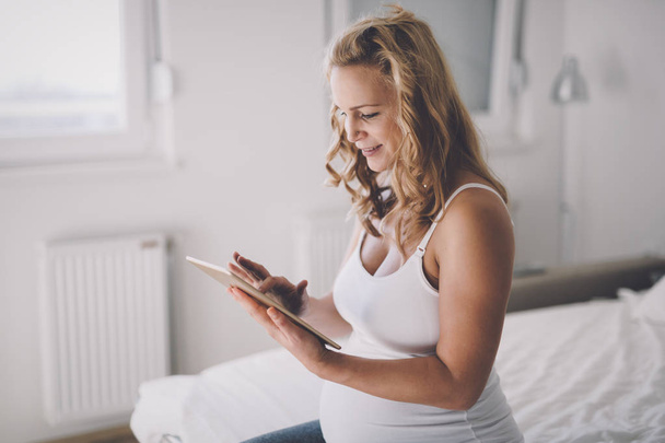 Pregnant woman using tablet - Foto, afbeelding