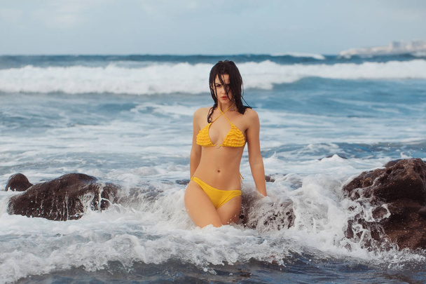 Pretty girl in sexi yellow swimsuit standing in white foam - Foto, Imagen