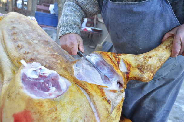 Sezione centrale del macellaio maschio taglio coscia di maiale con coltello - Foto, immagini