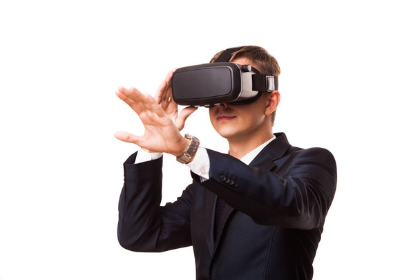Young handsome businessman in black suit wearing virtual reality goggles., isolated on white background - Фото, изображение