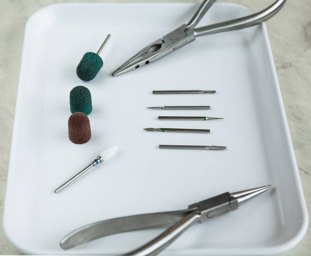 In linea ruspe mediche per podologia, tappi rossi e verdi, pinze sul vassoio medico bianco Attrezzature podologiche
 - Foto, immagini
