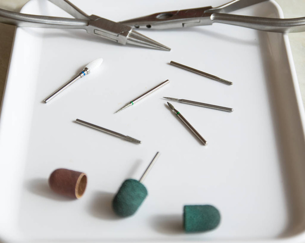 Medical instrument. Podoiogy burs, red and green caps, cutters on the white medical tray - Photo, Image