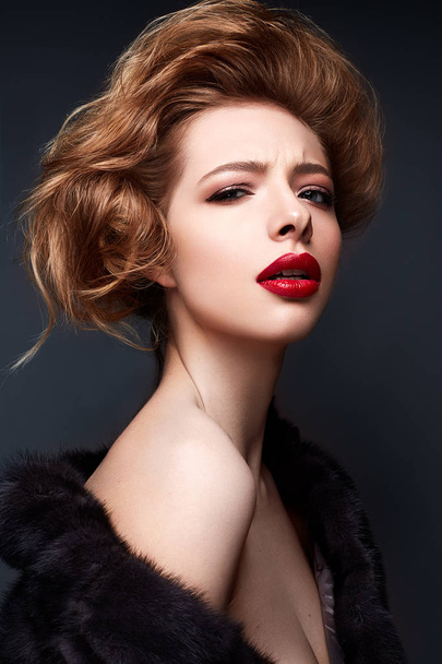 Young girl in a fur coat and bright makeup. Beautiful model with red lips and hairstyle - Photo, Image