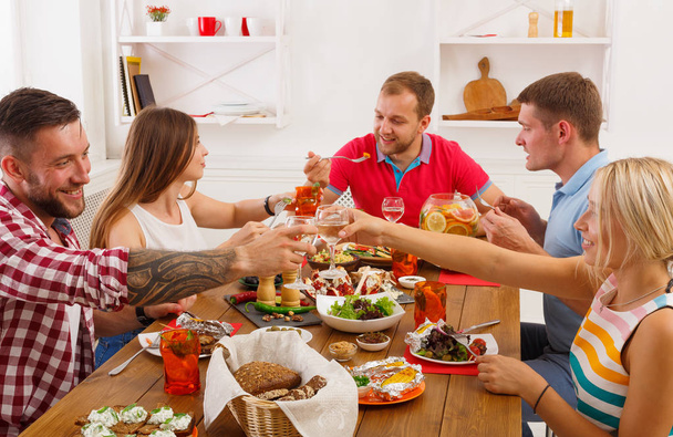 Οι άνθρωποι λένε ζητωκραυγές τσουγκρίζουν τα ποτήρια στο γιορτινό τραπέζι δείπνο κόμμα - Φωτογραφία, εικόνα