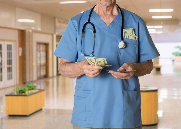 Senior doctor in scrubs counting cash - Photo, Image