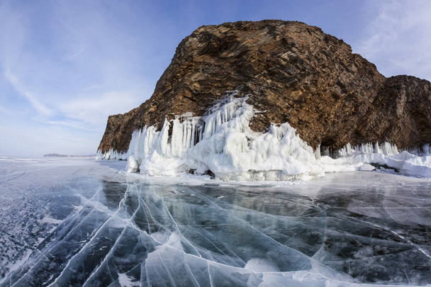 Winter Baikal with clear ice and reflection of rocks - Foto, afbeelding