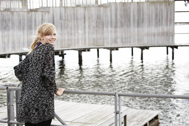 Young woman standing on pier - Zdjęcie, obraz