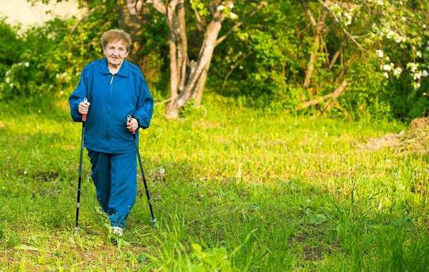 Active woman (85 years old) nordic walking outdoors. - Фото, зображення