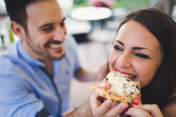 couple sharing slice of pizza in cafe - Foto, afbeelding