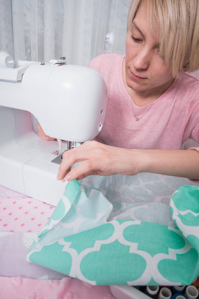 mooie vrouw naaister naaien op de naaimachine kleding. - Foto, afbeelding