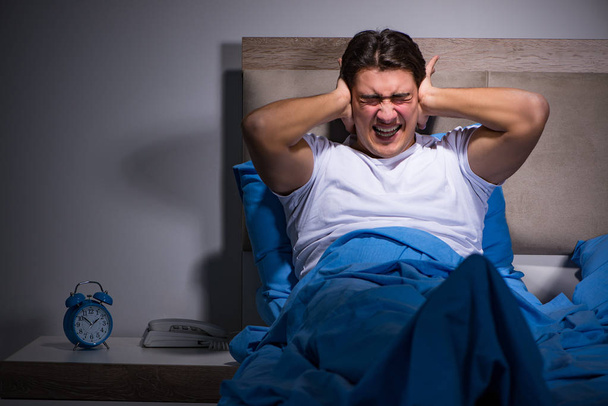 Young man struggling from noise in bed - Photo, Image