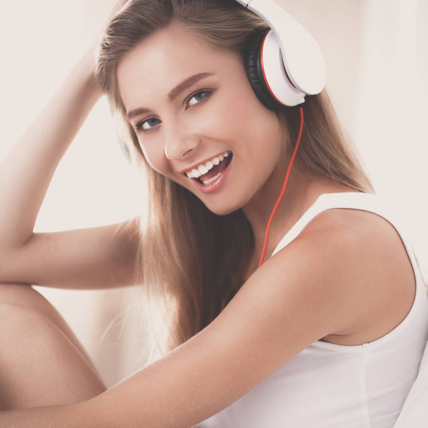 Portrait of beautiful woman in morning listening music sitting on bed at home - Foto, afbeelding
