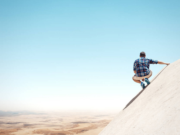 man sitting on a cliff and looking at the desert - Foto, Imagem