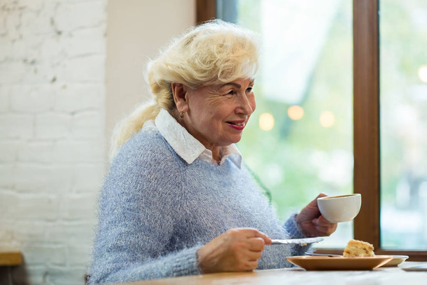 Femme âgée souriante tenant une tasse
. - Photo, image