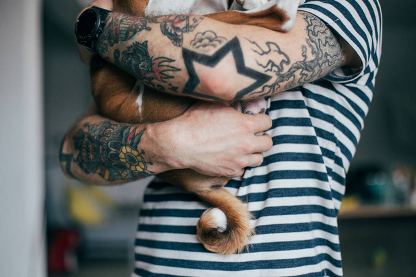 Чоловік тримає милого собаку
 - Фото, зображення