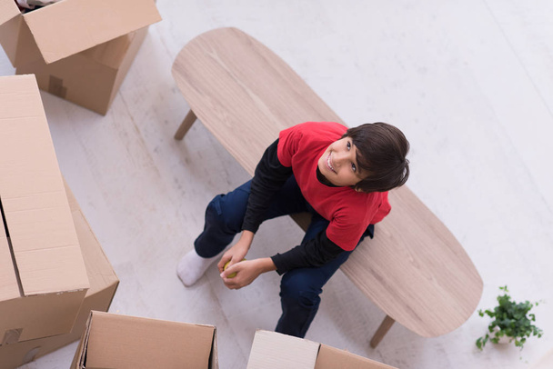 boy sitting on the table with cardboard boxes around him top vie - Photo, Image