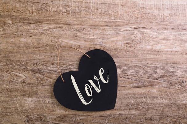Black heart on wooden background. Love design. - Fotó, kép