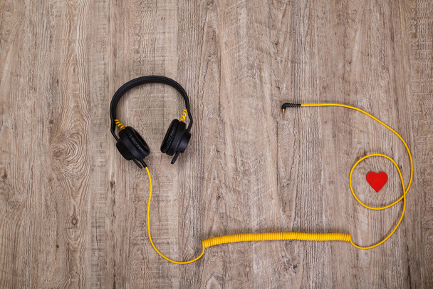 Headphones with red heart. Wooden background. - Foto, afbeelding