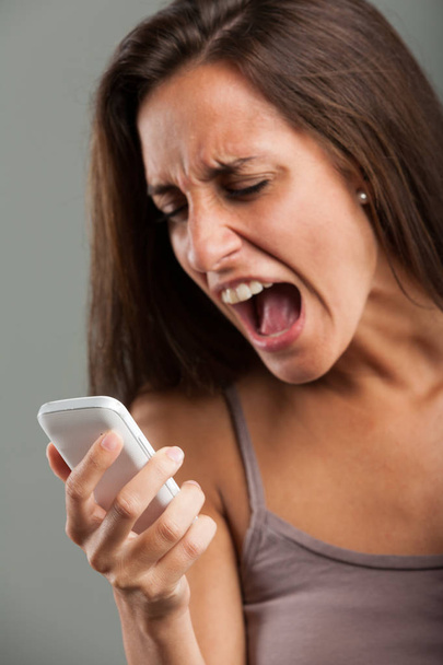 Разочарованная молодая женщина кричит на мобильный
 - Фото, изображение