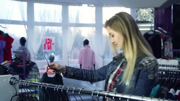 Aantrekkelijk meisje, het kiezen van kleding in het winkelcentrum - Video