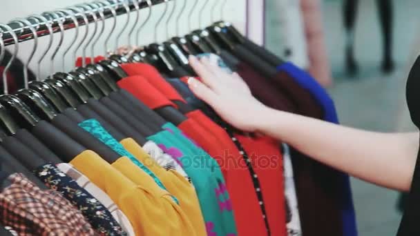 Frauenhände laufen über einen Kleiderständer und stöbern in einer Boutique. - Filmmaterial, Video