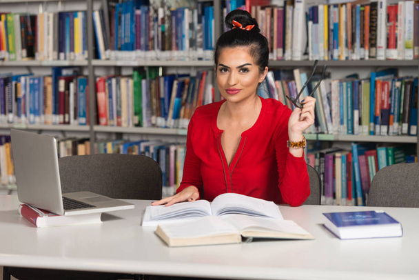 Jonge Student via haar Laptop In een bibliotheek - Foto, afbeelding