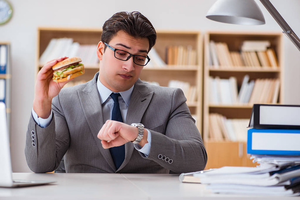 Голодний смішний бізнесмен їсть бутерброд з нездоровою їжею
 - Фото, зображення
