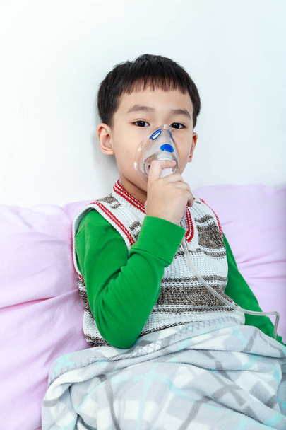 Aasialainen lapsi pitää maski-höyryinhalaattoria astman hoitoon
.  - Valokuva, kuva