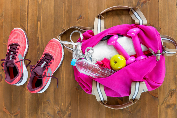 木製の床の上にオープン スポーツ バッグとピンクのランニング シューズを争う - 写真・画像