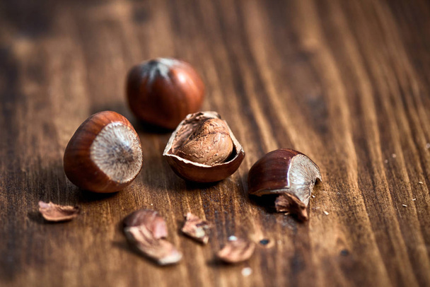 Cracked hazelnuts on wooden table - Фото, изображение