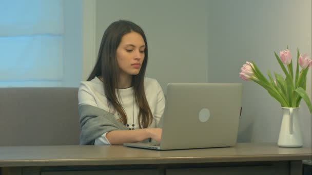 Csinos, fiatal nő dolgozik modern laptop otthon a kanapén - Felvétel, videó
