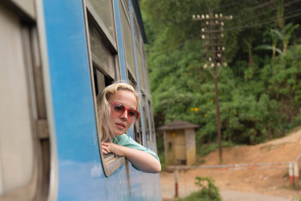 Blonde kaukasische Frau reitet Zug und schaut durch Fenster. - Foto, Bild