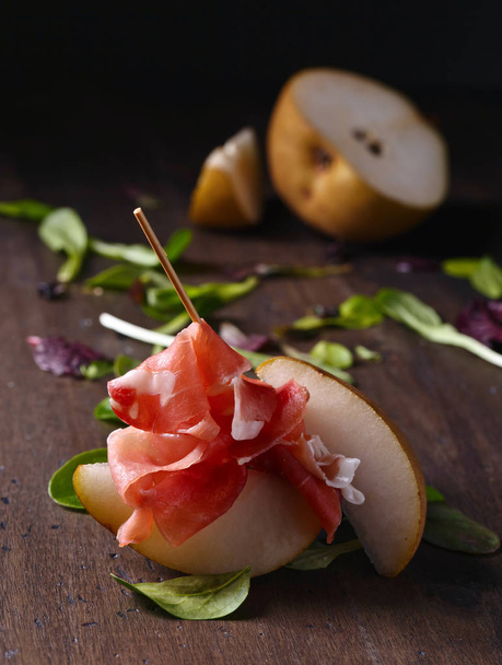 prosciutto with pear on a wooden table - Photo, Image