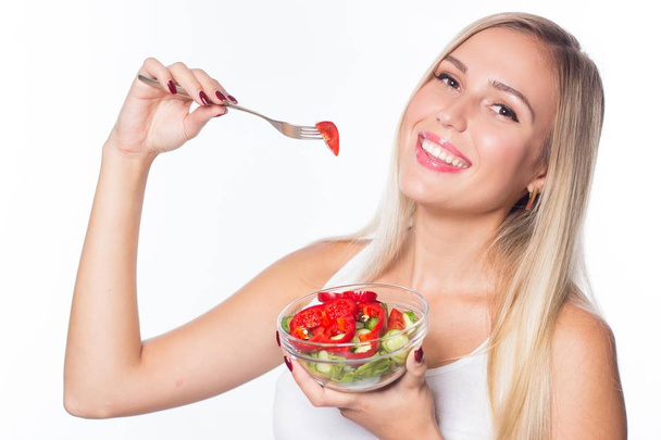 Young beautiful woman eats vegetable salad. Healthy eating. To be in shape. - Photo, Image