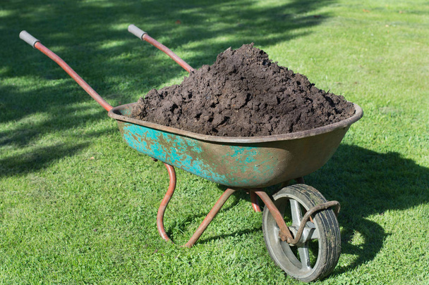 Garden-wheelbarrow filled with soil on a farm. - Foto, immagini