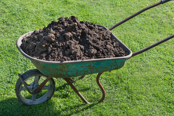 Garden-wheelbarrow filled with soil on a farm. - Photo, Image