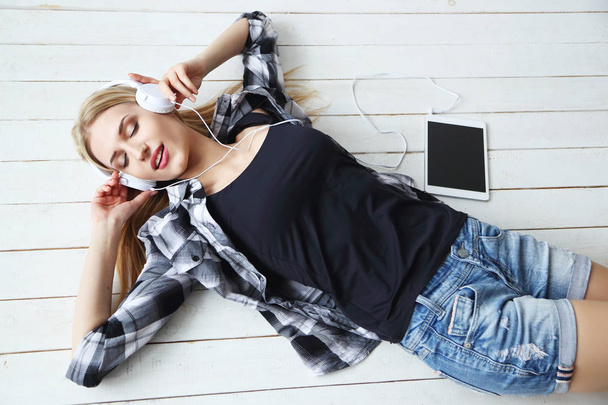 woman in headphones lying on floor  - Fotó, kép