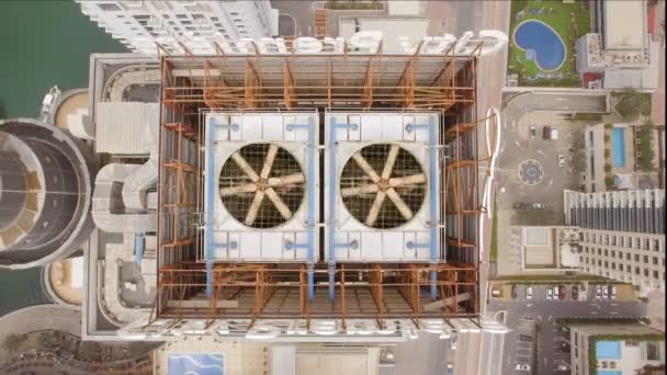 vista aérea de dos ventiladores de refrigeración girando en el techo del rascacielos. A la izquierda del edificio se puede ver el lago y a la derecha de la piscina
 - Imágenes, Vídeo