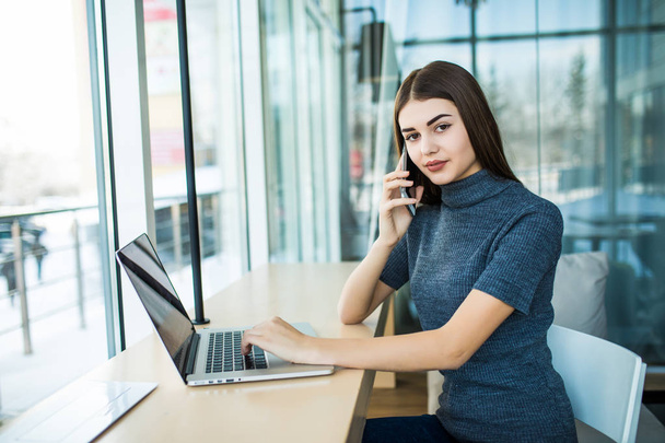 Портрет молодой предпринимательницы с деловым звонком в офисе. Женщина разговаривает по мобильному телефону
. - Фото, изображение