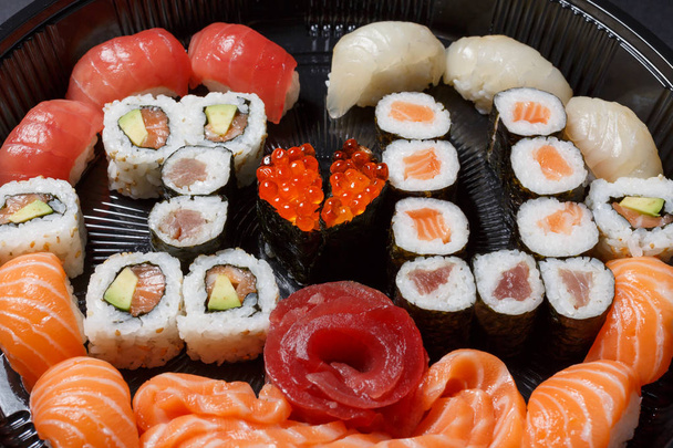 Μια μεγάλη σειρά από σούσι και ρόλους θέα από ψηλά. Πολλά τρόφιμα σε ένα πιάτο. Πιάτα από ωμό ψάρι ιαπωνικά τρόφιμα. Ένα πιάτο σε ρομαντικό ύφος. Σε αγαπώ. Καρδιά με κόκκινα ψάρια χαβιάρι - Φωτογραφία, εικόνα