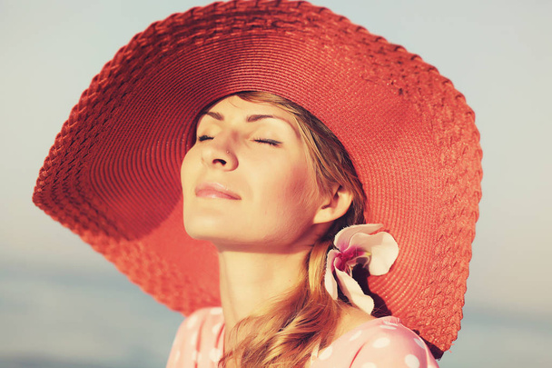 Portrait of a beautiful graceful woman in elegant pink hat with a wide brim. Beauty, fashion concept - 写真・画像