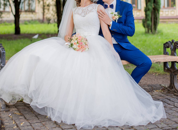 The bride and groom sit together on the bench - Фото, зображення