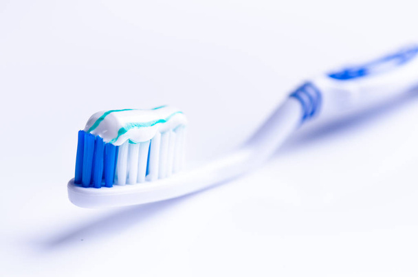 Toothbrush isolated on a white background with reflection and toothpaste. Blue plastic toothbrush. Concept of dental medicine.  - Fotografie, Obrázek