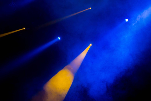 The blue-yellow light from the spotlights through the smoke in the theatre during the performance. Lighting equipment. - 写真・画像